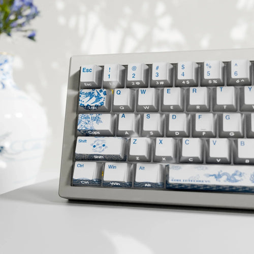 White mechanical keyboard with blue pottery-themed keycaps featuring floral and dragon patterns